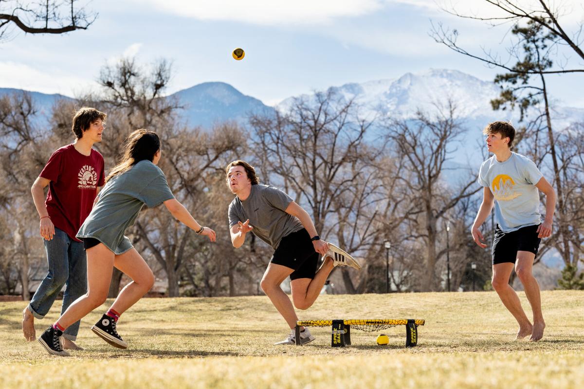 Tony Saenz ’24 (Adidas), Owen Stefanakos ’26 (jeans), Charlie Turner ’26 (light blue tee), and Charlotte Pulido ’24 (Converse) play spike ball in Tava Quad on 3/14/23. They play whenever it’s warm. Photo by Lonnie Timmons III / Colorado College
